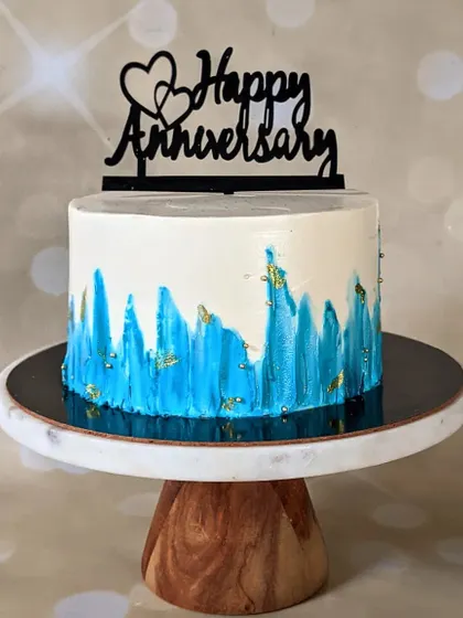 Simple yet beautiful cakes like this have my heart. This anniversary cake features an abstract, textured blue design on a white buttercream base, finished with a touch of edible gold leaf.