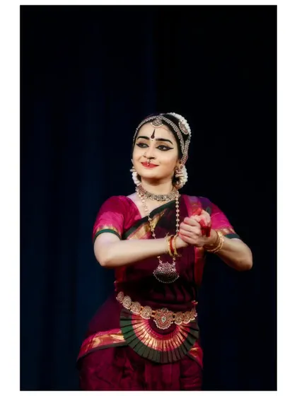 A gentle, expressive moment from a performance in Chennai. The hand gesture and soft smile convey a feeling of affection and tenderness.