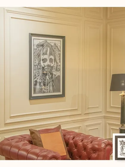 This striking portrait of an Ethiopian woman is a powerful piece of wall art. The black and white photography, framed in dark wood, adds a sense of depth and cultural richness to the room.