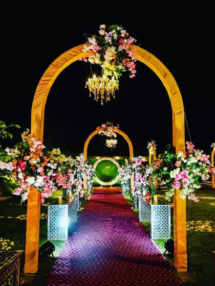 We create grand, welcoming entrances for your guests. This beautiful walkway features a series of golden arches adorned with flowers and hanging chandeliers, leading guests down a red carpet.