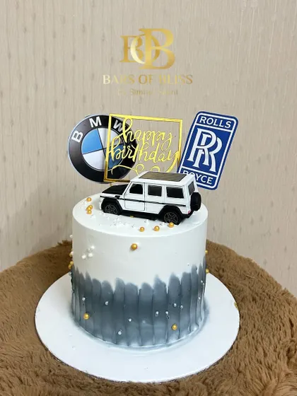A sleek and stylish cake for the luxury car enthusiast. This design features a grey and white watercolor effect, topped with logos of premium car brands like BMW and Rolls Royce, and a model G-Wagon.