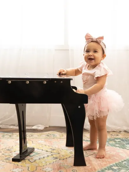 A tiny pianist for her first birthday. Using props like this miniature piano adds a touch of whimsy and fun to the session.