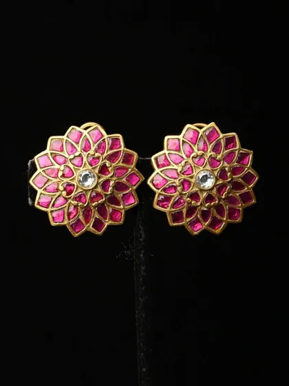 A pair of beautiful floral studs with vibrant pink meenakari enamel work. The gold-toned petals surround a single white stone at the center, creating a bright and cheerful look.