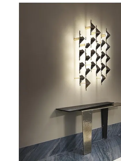 This custom wall sconce is installed above a minimalist console table, serving as a piece of illuminated art in a hallway. The design is both modern and timeless.