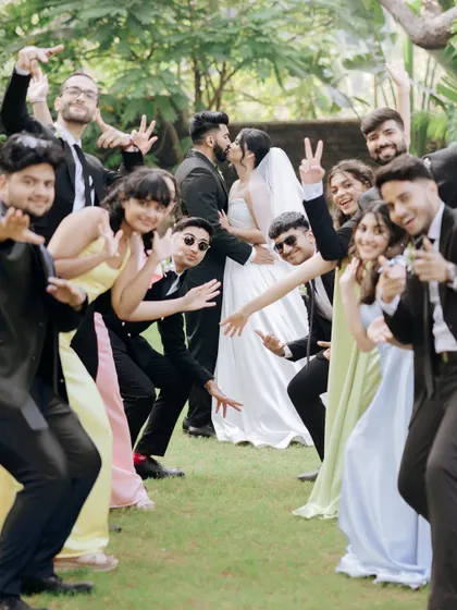 A fun and energetic photo of the wedding party, with everyone striking a pose around the happy couple.