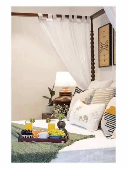 A closer look at the four-poster bed in the Goan holiday home. The design is light and airy, with simple tie-top curtains and a mix of patterned cushions that evoke a sense of sun and waves, perfect for a beachside retreat.