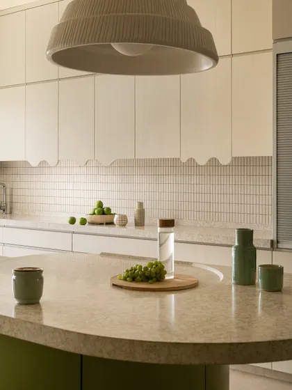 This fun, spacious kitchen was designed around a circular layout. An olive-green, curved island with a breakfast counter serves as the central cooking platform.