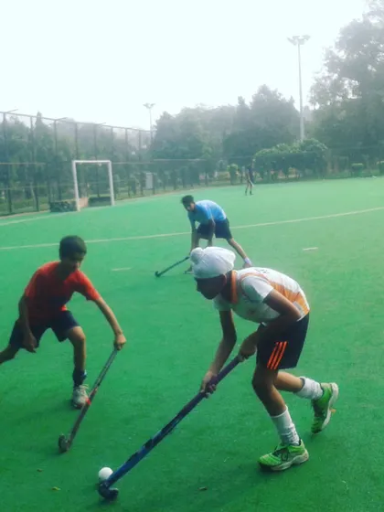 Young players engaged in a dribbling drill on a green turf. Mastering basic skills like ball control is the foundation of every great hockey player.