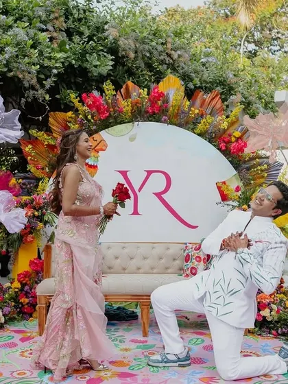 Capturing the essence of love amidst the vibrant chaos of a Goa Carnival theme. The couple strikes a playful pose against a colorful, floral photo-op I designed.