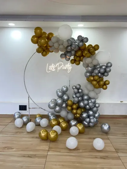 A classic "Let's Party" setup with a silver, gold, and white color scheme. The balloon-covered ring and neon sign create a timeless and celebratory photo spot.
