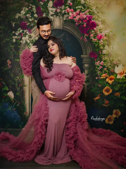 A romantic couple's portrait against a floral arch. The rich color of her ruffled gown and his dark shirt create a beautiful contrast.