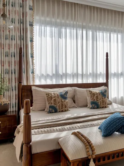 This bedroom is a cozy retreat designed for comfort and nostalgia. The classic four-poster wooden bed, patterned curtains, and soft, layered linens create a warm and welcoming ambiance, perfect for a grandparents' room.