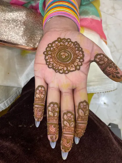 A classic party mehendi design. It features a simple mandala on the palm with matching floral details on each finger.
