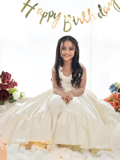 A happy smile from the birthday girl in her beautiful white dress. The simple "Happy Birthday" banner adds a festive touch.