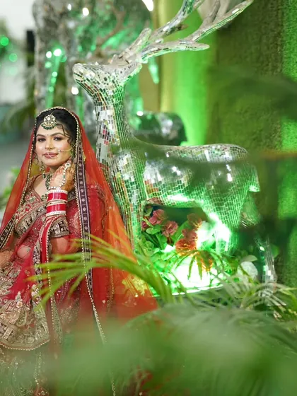 A creative portrait of the bride next to a mirrored deer statue. The green lighting and unique prop make this a memorable shot.