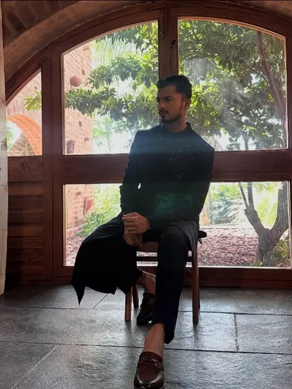 A moment of quiet reflection during a shoot for men's ethnic wear. The silhouette of the bandhgala against the arched window creates a powerful, regal image.