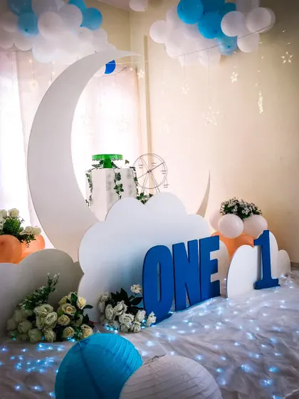 A "To the Moon and Back" theme for a first birthday. The crescent moon prop and cloud cutouts create a dreamy, celestial atmosphere.