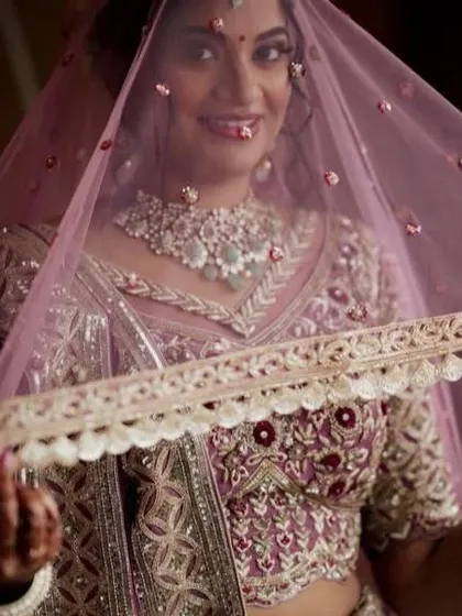 A beautiful shot of the bride under her veil. The makeup is designed to look soft and ethereal, even under the delicate fabric of the dupatta.