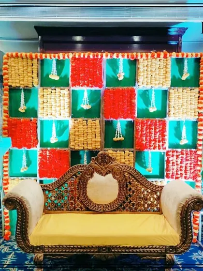 A full view of a marigold checkerboard stage setup in a banquet hall. The design includes side floral arrangements and lighting to create a festive focal point for the event.