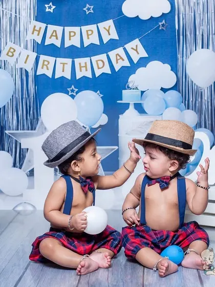Twin boys celebrating their first birthday in style! Dressed in matching outfits with hats and bow ties, they create an adorable and interactive scene.