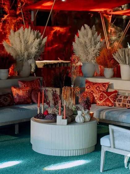This outdoor lounge area was designed with warm red and orange tones. We used dried grasses and floral arrangements to define the space, set against a backdrop of dramatic stage lighting for the evening's performances.