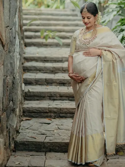 Our beautiful mommy-to-be, glowing in a traditional white and gold saree for her maternity shoot. The makeup is soft and radiant, celebrating this special time in her life.