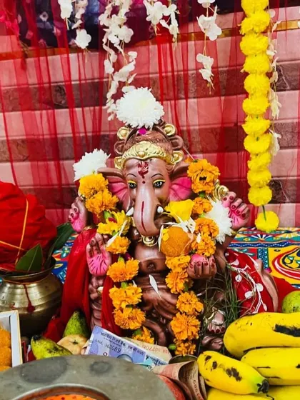A close-up of a beautifully adorned Ganpati idol, surrounded by fresh flowers and offerings. Sometimes the simplest decorations, done with heart, are the most beautiful.
