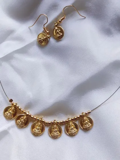 A delicate and minimalist gold-finish necklace with Lakshmi coins, paired with matching earrings. A lovely choice for a simple, traditional look.
