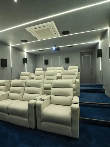 The combination of cool gray acoustic panels, blue carpeting, and bright white LED strip lighting gives this Madurai home theater a distinctly modern and futuristic feel. The design is both visually striking and acoustically functional.