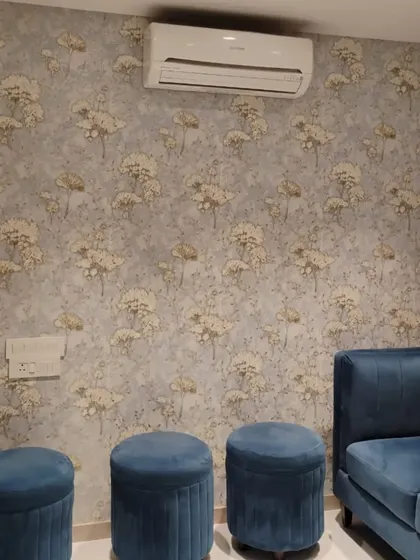 This living room features a soft, floral wallpaper that complements the blue velvet furniture. The subtle pattern adds a touch of elegance and warmth, making the seating area feel more inviting.