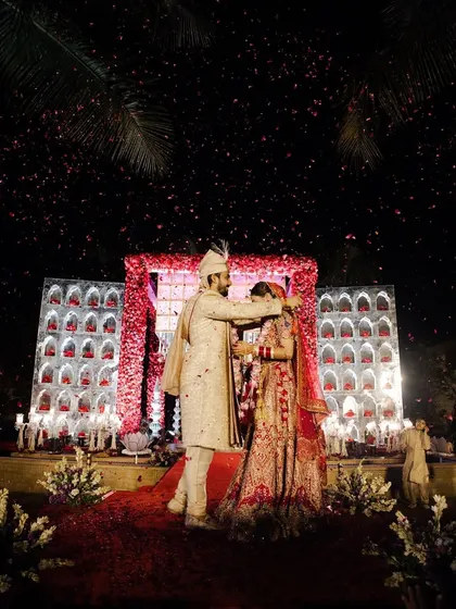 The varmala exchange under the stars. The grand mandap, the shower of petals, and the beautiful night sky all come together to create a scene straight out of a movie.
