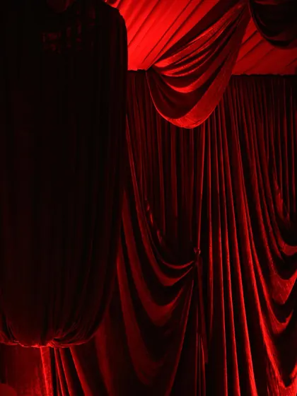 The dramatic sweep of heavy red velvet curtains, expertly lit to highlight their texture and deep color. This forms the foundation of a truly immersive event space.