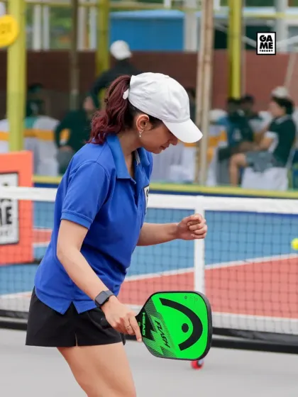 A focused player returns a low shot at the net during a B'luru Open match. Net play is a crucial part of competitive pickleball.