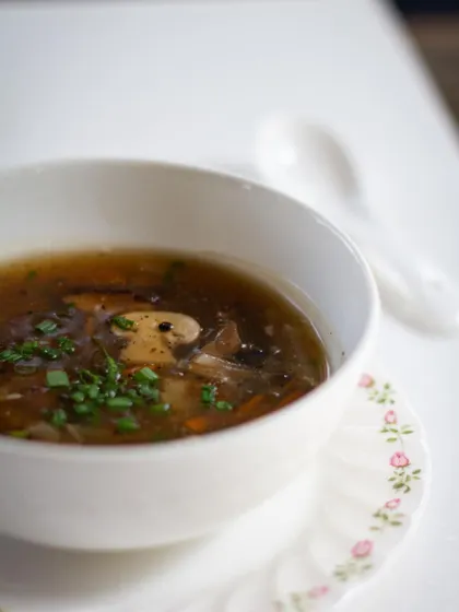 A clear mushroom consommé, a classic dish that teaches the art of clarification and extracting pure flavor.