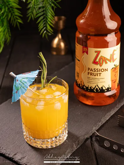 A dark and moody shot of a passion fruit mocktail. The slate background and dramatic lighting give it a sophisticated, evening-at-the-bar feel.