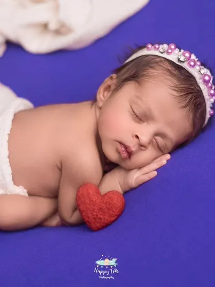 Simple, classic, and all about the baby. This side-lying pose on a vibrant purple backdrop highlights the baby's delicate features and peaceful sleep.
