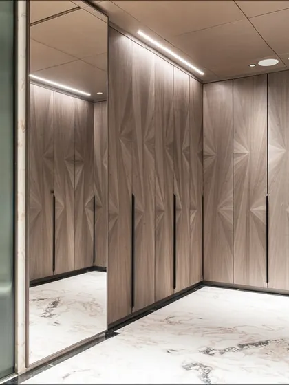 A walk-in closet connected to the master bedroom, featuring custom shutters crafted in starburst-dyed Koto veneer. The geometric pattern adds a layer of visual interest to the functional space.
