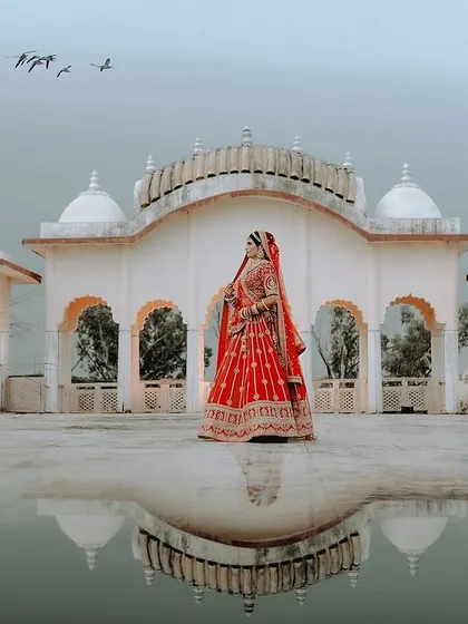 An artistic bridal portrait using a reflection to create a surreal and beautiful image of the bride against the palace and sky.