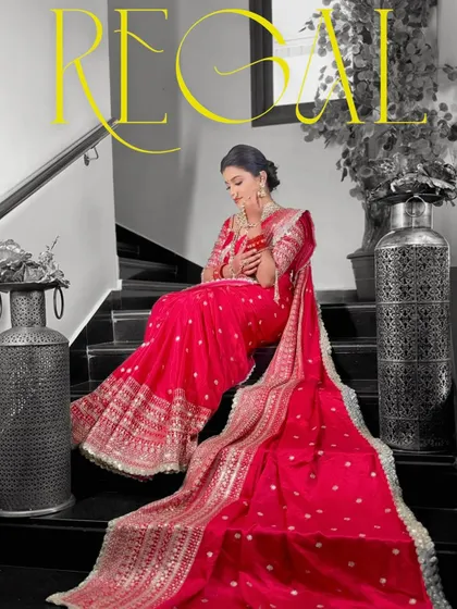 The full, regal flow of a heavily embroidered red bridal saree. The long pallu is draped to create a sense of royalty and grandeur.