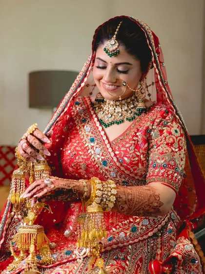 A bride admiring her kaleeras, dressed in a beautiful red lehenga. I provide outfits that honor all the beautiful traditions of an Indian wedding.