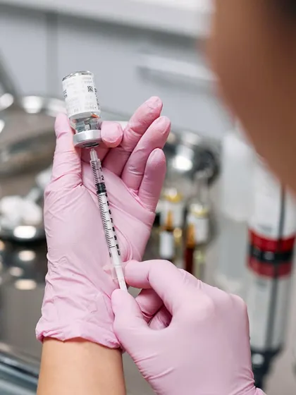 A clinician preparing a dermal filler injection. We use these gel-like substances, typically made of hyaluronic acid, to add volume to areas like the cheeks, lips, and around the mouth.