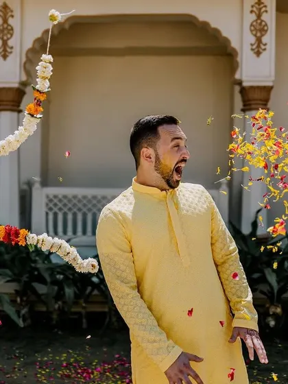 A candid shot of the groom's surprised reaction as he's showered with flower petals. These unscripted moments make for the best memories.