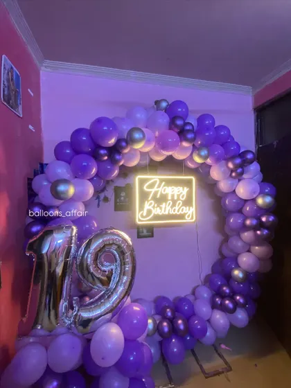 A 19th birthday party with a purple theme. The decor includes a full circular balloon arch and silver foil number balloons.
