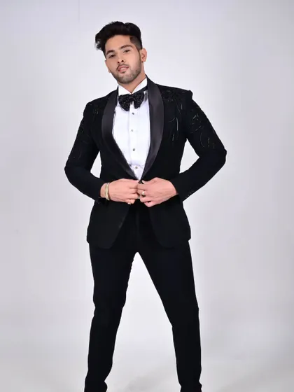 A model adjusting his bespoke tuxedo jacket, which features subtle tonal embroidery and a satin shawl lapel for a touch of luxury.