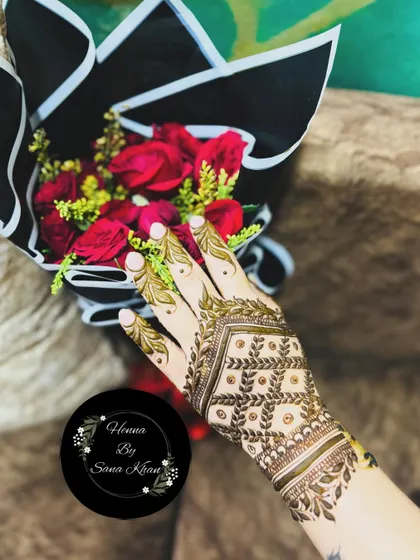 This elegant design features a 'jaal' or net pattern on the back of the hand, framed by a leafy border. It's a sophisticated and modern choice, shown here with a beautiful bouquet of roses.