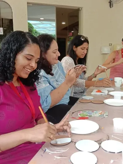 A group of mothers enjoying the decoupage workshop, laughing and creating together.