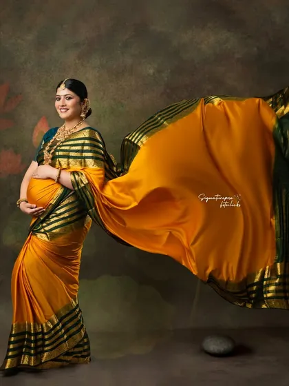 The vibrant yellow saree with its flowing pallu creates a stunning visual against a painterly background.