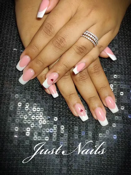 A classic French manicure on long, square-tipped nails, accented with a tiny red heart on two fingers. It's a sweet and personal touch to add to a timeless style.