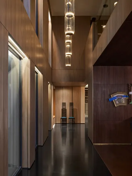 A passage to the dining room at the Baid Residence, designed as an elegant gallery. It features modern lighting from Flos, statement chairs by Pallucco, and black granite flooring for a timelessly sophisticated look.