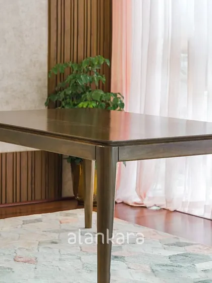 A detailed shot of the Zircon dining table, highlighting the beautiful grain of the teak wood and the expert craftsmanship of its construction.